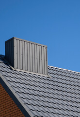 Fototapeta na wymiar Grey corrugated metal profile roof installed on a modern house. The roof of corrugated sheet. Roofing of metal profile wavy shape. Modern roof made of metal. Metal roofing.