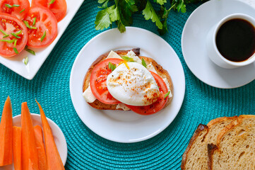 Sandwich with whole grain bread, goat cheese, fresh tomatoes and poached egg. Delicious simple breakfast. Proper nutrition. Top view, flat lay