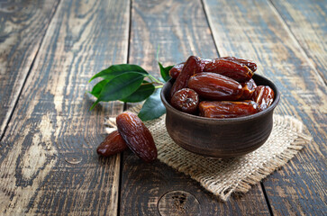 Dried dates fruit in ceramic bowl on old wooden table. Highly valuable food product. Dried fruits.