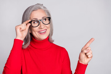 Photo of attractive dreamy happy nice old woman point fingers empty space sale isolated on grey...