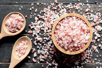 Pink salt in a wooden bowl, placed on a black wood, Himalayan salt.