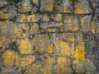 Ancient stone wall covered with moss, close-up. Natural stone background, texture