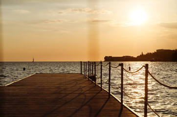Obraz premium Picturesque seaside resort town in Slovenian coast against orange sunset sky in summer. Scenic view to Adriatic sea in the evening. Travel concept. 