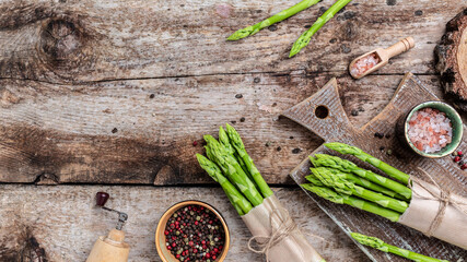 Fototapeta na wymiar Bunches of green asparagus, raw stems of asparagus on a wooden background