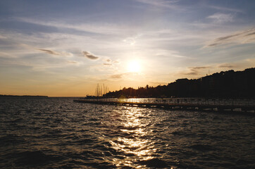 Picturesque seaside resort town in Slovenian coast against orange sunset sky in summer. Scenic view to Adriatic sea in the evening. Travel concept. 