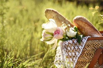 Bouquet of flowers and baguettes in a wicker basket in the garden.