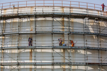 Fototapeta premium Construction workers tank oil installing scaffolding