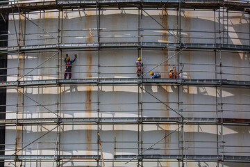 Construction workers tank oil installing scaffolding