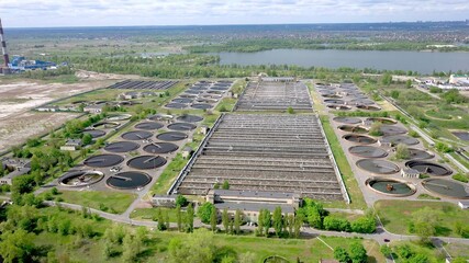 Aerial shot of a wastewater treatment plant and distant skyline. Big city waste processing concept