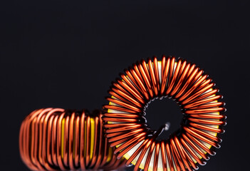 Close-up of copper wire coil on black background. - obrazy, fototapety, plakaty