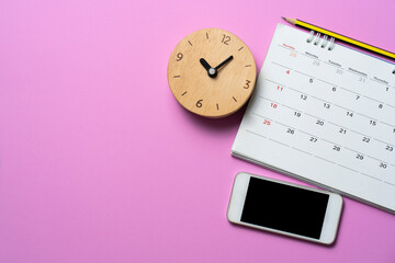close up of calendar, clock , mobile phone on the pink table background, planning for business meeting or travel planning concept
