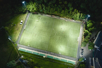 Stadium at night. Night football match. Two teams play football under the spotlights. Night workout. Preparation for the match. Aerial shot with a drone from a altitude - 434115636