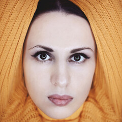 Close-up portrait of a beautiful young woman posing in bright yellow knitted sweater. Knitwear fashion.