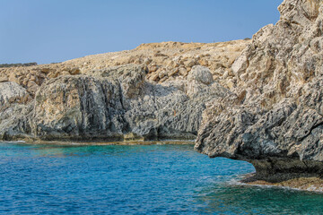 Small backwater surrounded by a stone cliff with azure water in Cyprus