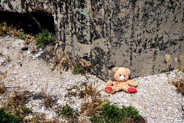 lost teddy bear supported by a World War II concrete bunker on the Black Sea beach  - Olimp, Mangalia, Constanta county, Dobrudja, Romania - obrazy, fototapety, plakaty