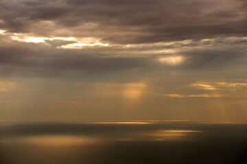 Fototapeta na wymiar Sun rays shining through clouds on sea surface