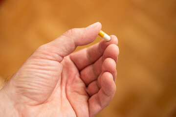 Caucasian male hand holding a medical pill in between his fingers shallow depth of field