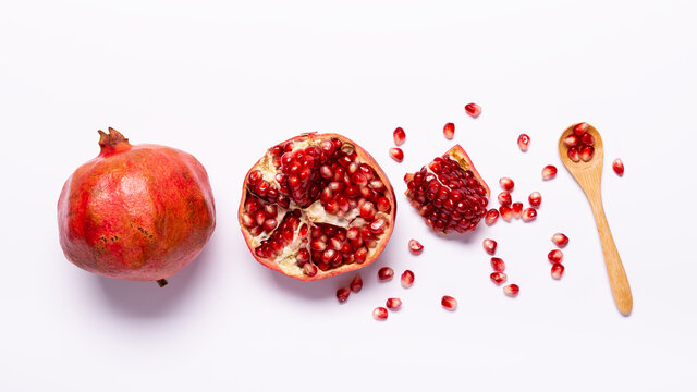 Top view on white background, fresh pomegranate fruit with scattered grains