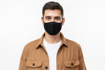 Young man wearing trendy brown workwear shirt and black face mask standing isolated on gray background