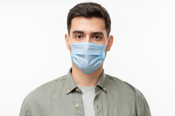 Young handsome man wearing shirt and medical mask, standing isolated on gray background