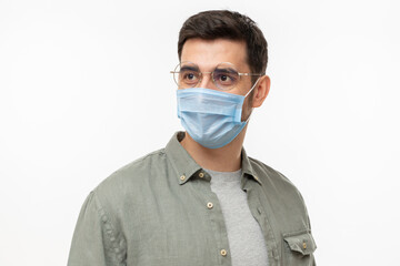 Young man wearing shirt, glasses and medical mask, looking away, isolated on gray background