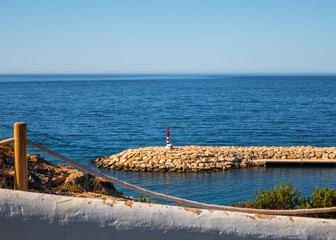 Fototapeta na wymiar Maritime landscape with a breakwater with a small red lighthouse, in Moraira, Alicante (Spain)