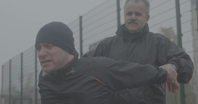 Training with a coach, a Paralympian man with defective legs sitting in a wheelchair exercise for training hands on the street outside