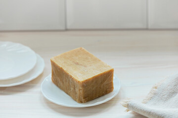 Natural handmade soap for washing dishes in the white plate. Eco-friendly home goods.