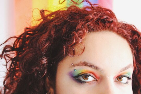 bright closeup portrait of queer young womans eye makeup of lgbtqia+ pride flag - spectrum of colors