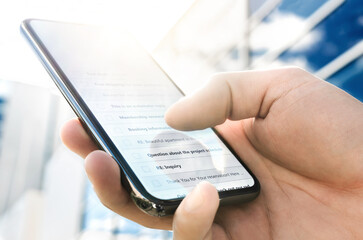 Email inbox with message list in phone. Business man using smartphone outside modern corporate office in urban city on a sunny morning. Person checking cellphone to read new mail text, message or spam