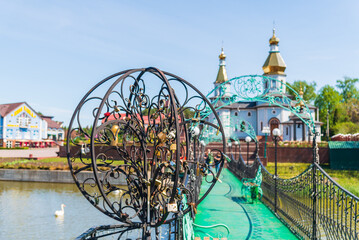 Bridge with padlocks over the river with a church on the background