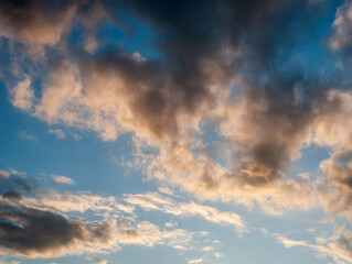 Fototapeta na wymiar Layered Clouds in Evening Light of Sunset on Blue Sky Background - Overcast Western Sky in Spring Dusk Time - Belarus Minsk