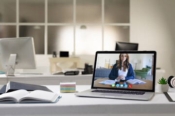 Caucasian woman having business video call on screen of laptop on desk