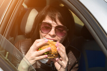 Happy young woman having lunch in the car. Sunglasses