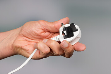 a hand is holding a three pin power plug