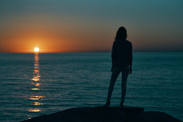 woman at sunset sea silhouette on the shore and beach sky