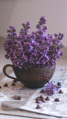 Decorative composition with a Bouquet of lilacs. Clay cup of tea and chocolate cake. A bouquet of lilacs in a vase. Spring floral background with lilacs in the interior. 
