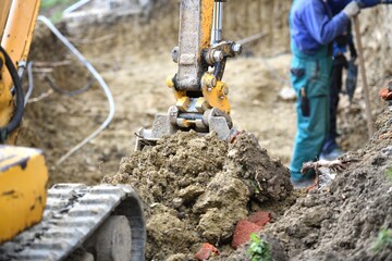 A combination of heavy excavator equipment and human masonry work in building a house © Pavol Klimek