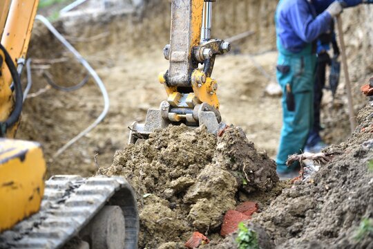 A combination of heavy excavator equipment and human masonry work in building a house