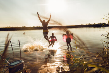 Fototapeta Friends having fun enjoying a summer day swimming and jumping at the lake. obraz