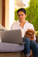 a young woman working and smiling in her home with her pet 