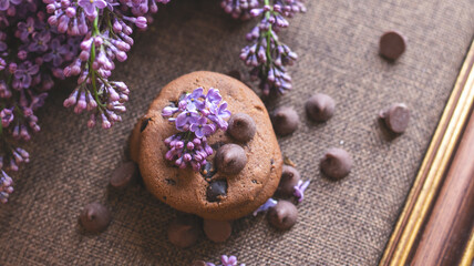 Decorative composition with a Bouquet of lilacs. Clay cup of tea and chocolate cake. A bouquet of lilacs in a vase. Spring floral background with lilacs in the interior. 