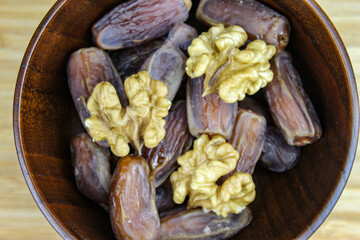 Wooden bowl with dates and walnut kernels. Fruit on a wooden tray. Fruit dates. Walnut kernels.