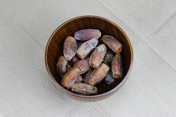 Wooden bowl with dates on the table. Fruit on a wooden tray. Fruit dates. Walnut kernels. The concept of Ramadan.