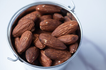 Almonds in zinc bucket, viewpoint on a marble background flat lay