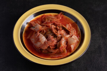 Lettuce kimchi in yellow plate on black background Flat lay copy space