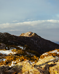 Beautiful view of the rocky snowy mountains gleaming under the cloudy blue sky