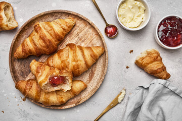 Fresh croissants with butter and strawberry jam for breakfast.