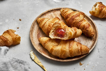Fresh croissants with butter and strawberry jam for breakfast.