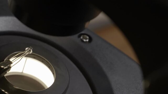 Pan over diamond grading device microscope in lab to certify gem and value. Round diamond sitting in special device for gemology to evaluate its grade and price to be sold in store or trade in market